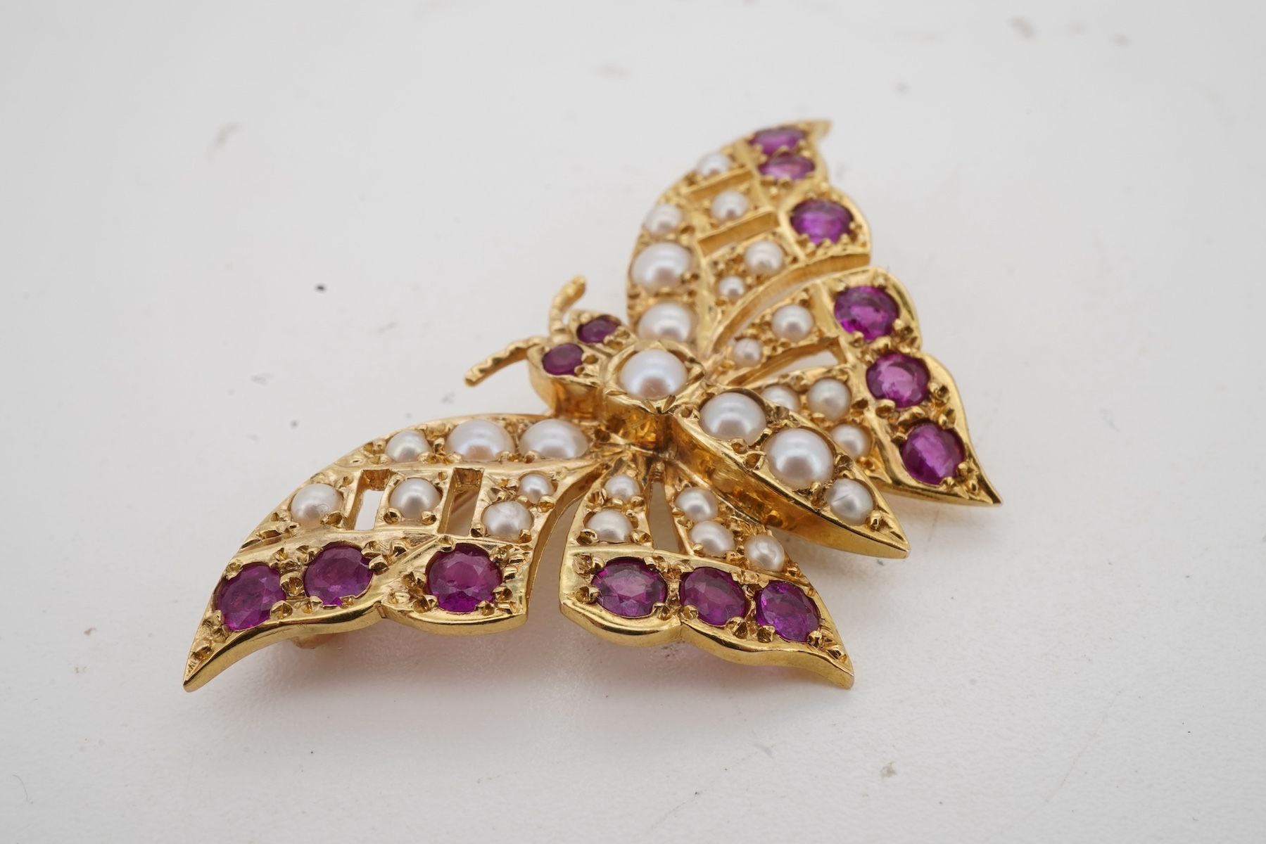 A ruby and split pearl butterfly brooch, set with half pearls and circular-cut rubies, mounted in 9ct gold, wingspan 4cm, British hallmarks, gross weight approximately 6 grams, pearls untested